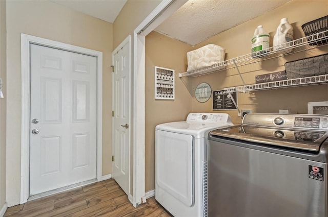 clothes washing area featuring washer and dryer, laundry area, light wood-style flooring, and baseboards