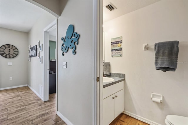 bathroom featuring vanity, wood finished floors, visible vents, and baseboards