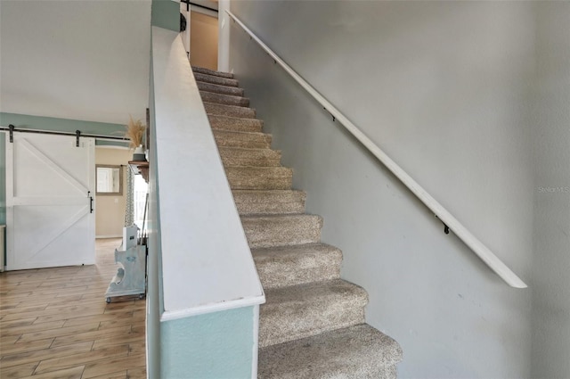 staircase featuring wood finished floors and a barn door