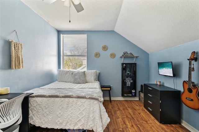 bedroom with a ceiling fan, lofted ceiling, dark wood-style flooring, and baseboards