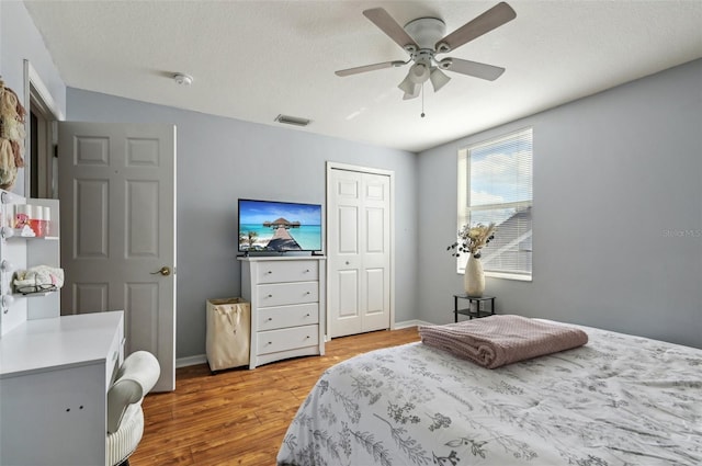 bedroom with baseboards, visible vents, a ceiling fan, wood finished floors, and a textured ceiling