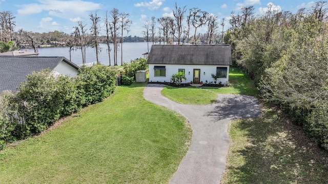 view of front of home featuring driveway, a water view, a front lawn, and roof with shingles