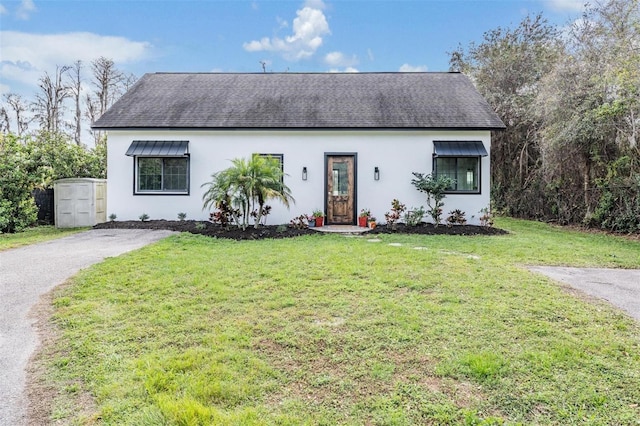 single story home with a front yard, roof with shingles, driveway, and stucco siding