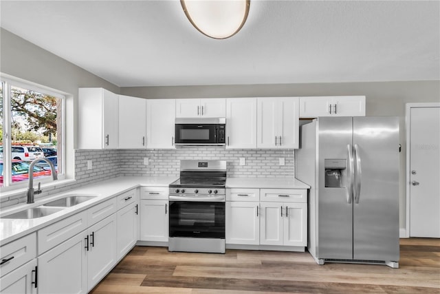 kitchen featuring white cabinetry, stainless steel appliances, a sink, and light countertops