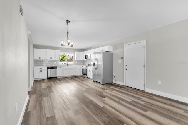 kitchen featuring light wood-style flooring, white cabinetry, stainless steel appliances, and backsplash