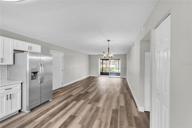 unfurnished dining area with light wood-style floors, baseboards, and a notable chandelier