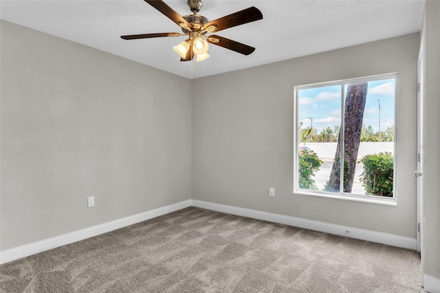 carpeted spare room featuring a ceiling fan and baseboards