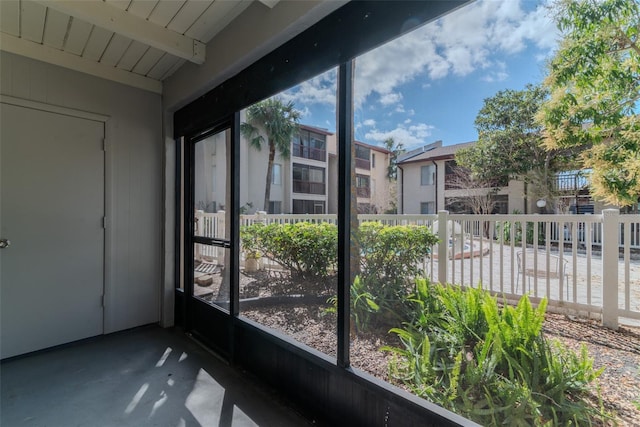 unfurnished sunroom featuring beam ceiling