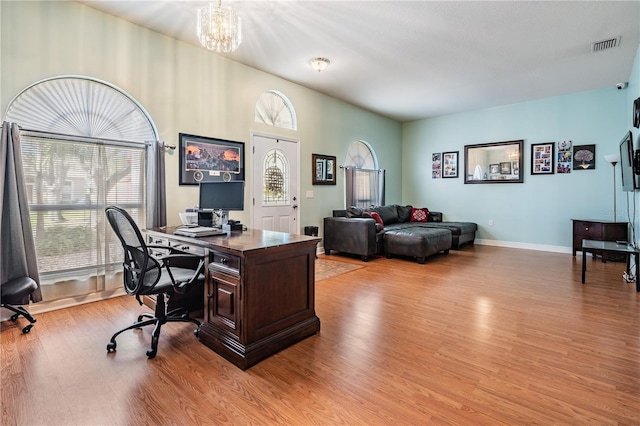 office area with a healthy amount of sunlight, baseboards, light wood finished floors, and a notable chandelier
