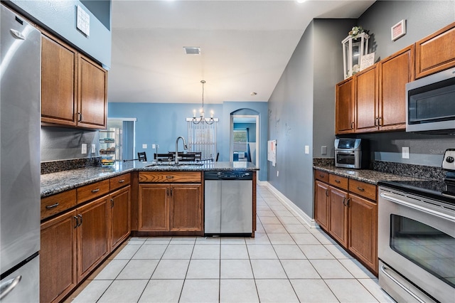 kitchen with a sink, light tile patterned floors, a peninsula, a chandelier, and stainless steel appliances