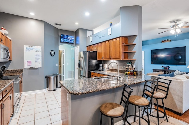 kitchen featuring brown cabinets, ceiling fan, open shelves, appliances with stainless steel finishes, and a sink