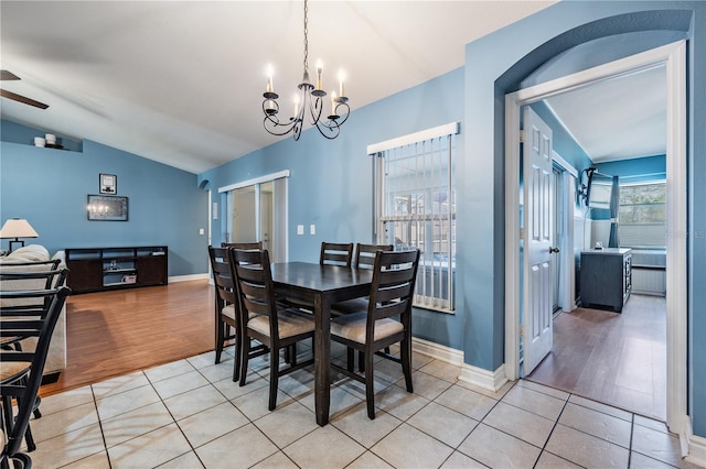 dining room with baseboards, vaulted ceiling, light tile patterned floors, and ceiling fan with notable chandelier