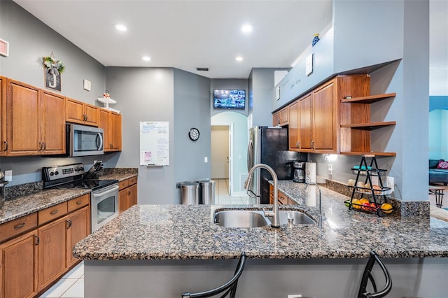 kitchen with open shelves, appliances with stainless steel finishes, a sink, dark stone counters, and a peninsula