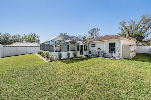 back of house featuring a fenced backyard, glass enclosure, stucco siding, and a yard