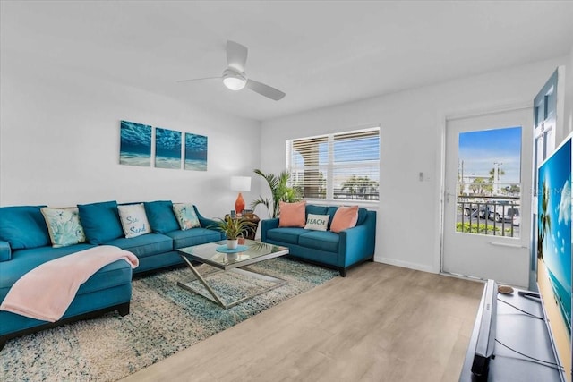 living area with wood finished floors, a ceiling fan, and baseboards