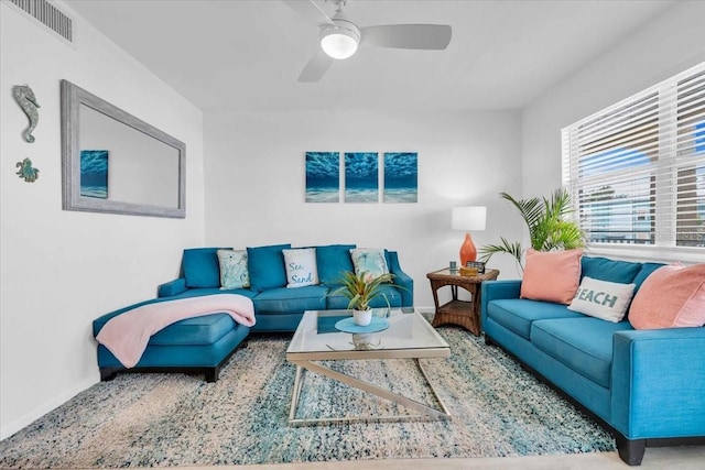 living room with a ceiling fan, visible vents, and baseboards