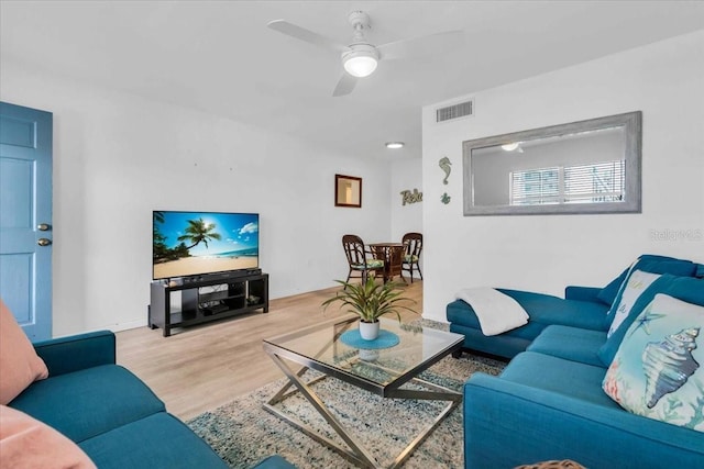 living room featuring light wood finished floors, visible vents, and a ceiling fan