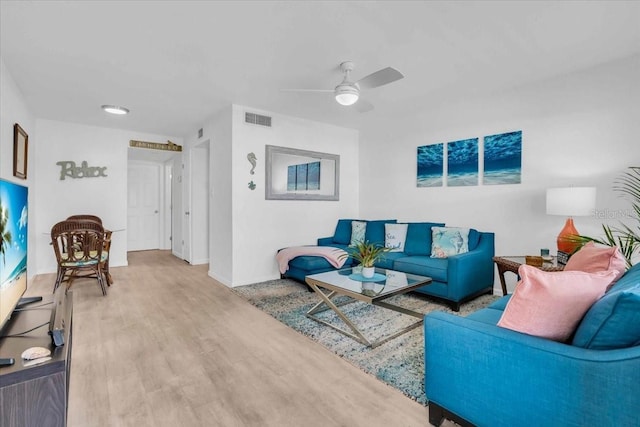 living area featuring a ceiling fan, visible vents, light wood-style flooring, and baseboards