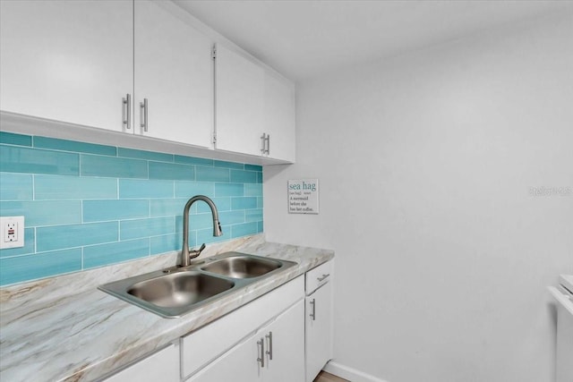 kitchen with backsplash, white cabinets, a sink, and light countertops