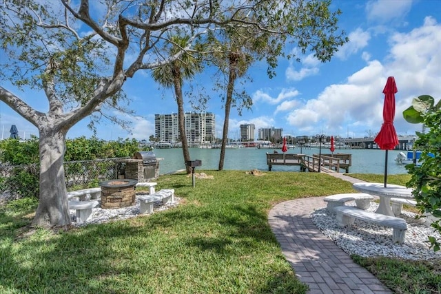 view of home's community with a view of city, a water view, a lawn, a boat dock, and a fire pit