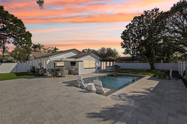 pool at dusk with a fenced in pool, a fenced backyard, and a patio