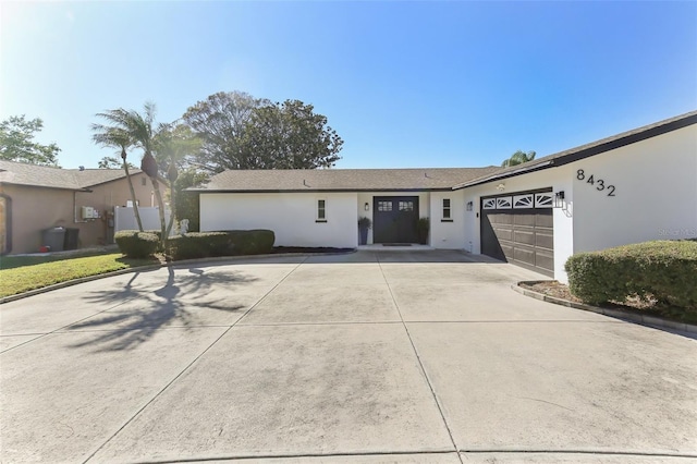 single story home with concrete driveway, an attached garage, and stucco siding