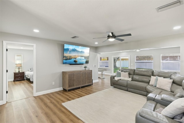 living area featuring a wealth of natural light, visible vents, and wood finished floors