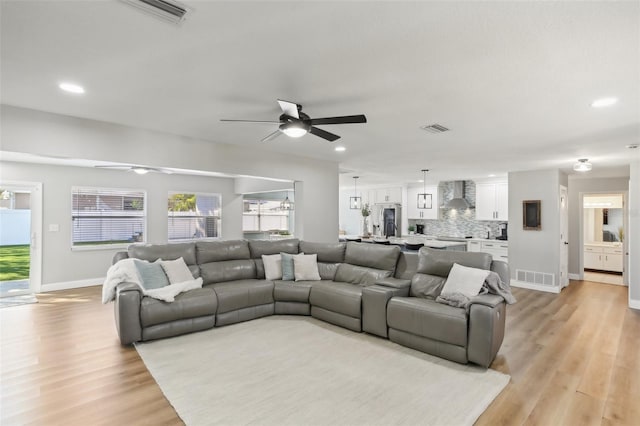 living room featuring light wood-type flooring, visible vents, and recessed lighting