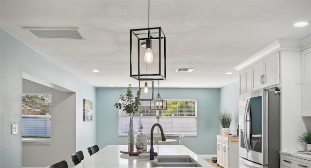 kitchen featuring smart refrigerator, visible vents, white cabinetry, and a sink