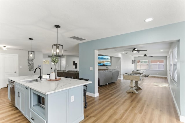 kitchen featuring an island with sink, open floor plan, a sink, and hanging light fixtures