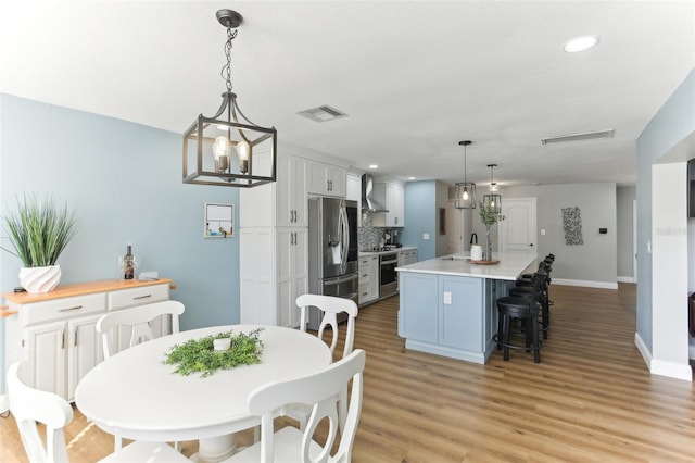 dining space featuring visible vents, baseboards, light wood-style flooring, an inviting chandelier, and recessed lighting