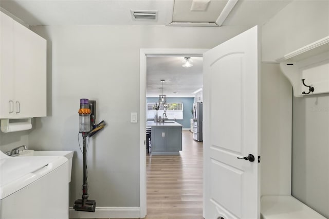 laundry room featuring washer / dryer, cabinet space, visible vents, light wood-type flooring, and a sink