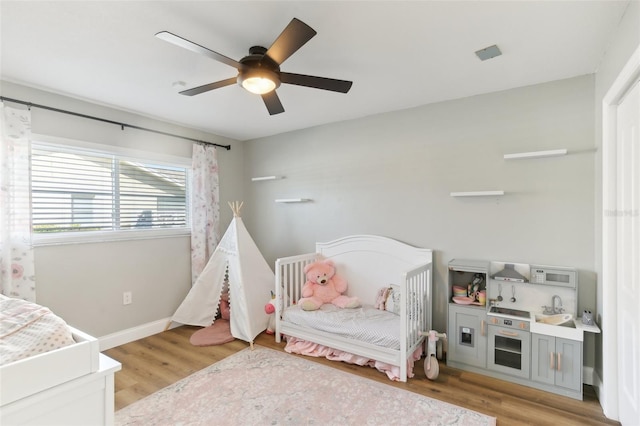 bedroom featuring ceiling fan, light wood-style flooring, and baseboards