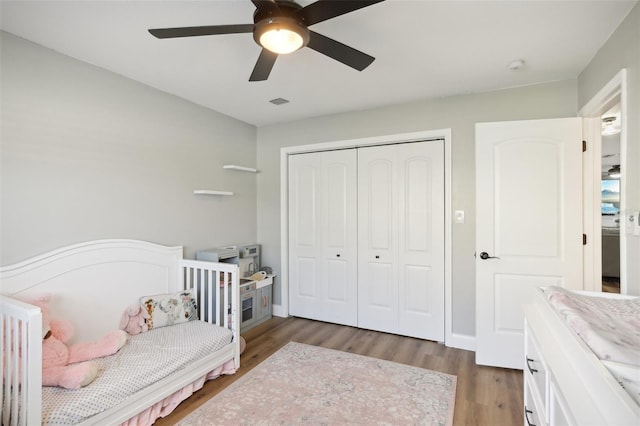 bedroom featuring dark wood-type flooring, visible vents, a ceiling fan, baseboards, and a closet