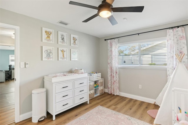 bedroom featuring light wood finished floors, visible vents, baseboards, and a ceiling fan