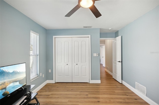 bedroom featuring light wood-type flooring, a closet, visible vents, and baseboards