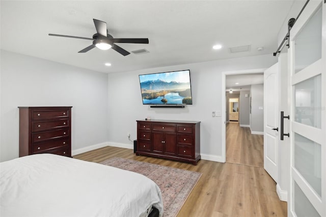 bedroom featuring recessed lighting, light wood-style flooring, baseboards, and a barn door