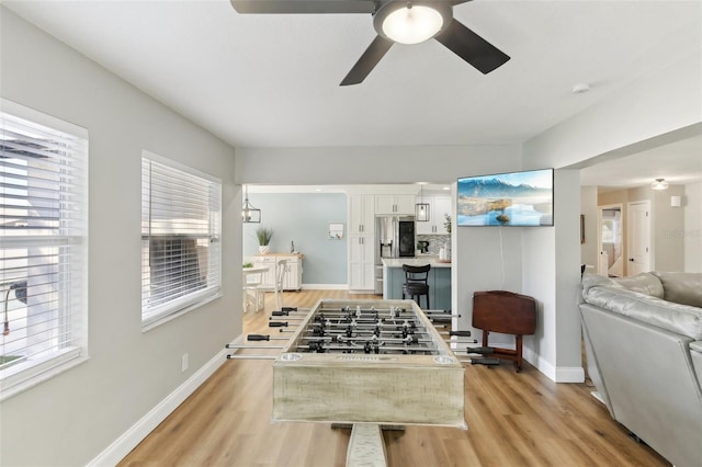 playroom with a ceiling fan, light wood-style flooring, and baseboards