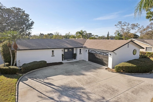 ranch-style house featuring a garage, concrete driveway, roof with shingles, and stucco siding