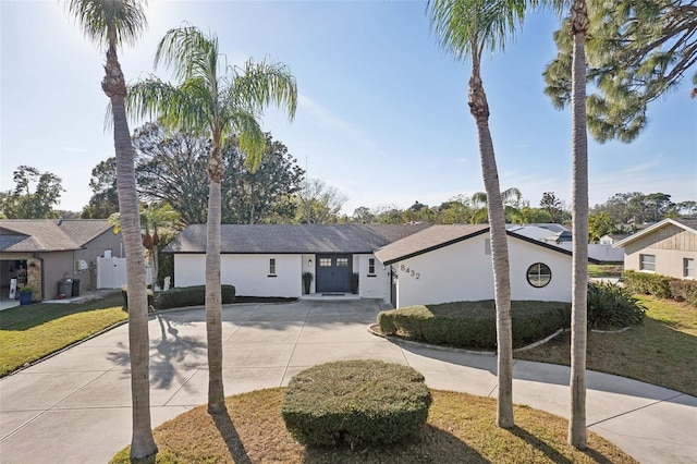 single story home with curved driveway, a front yard, a residential view, and stucco siding