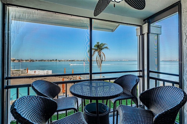 sunroom / solarium featuring a water view and a ceiling fan