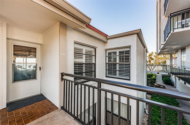 view of exterior entry featuring a balcony and stucco siding