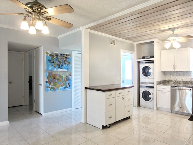 kitchen with stacked washer and dryer, ornamental molding, stainless steel dishwasher, tasteful backsplash, and dark countertops