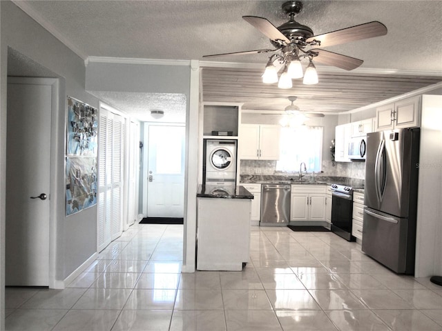 kitchen with dark countertops, appliances with stainless steel finishes, ornamental molding, a textured ceiling, and a sink