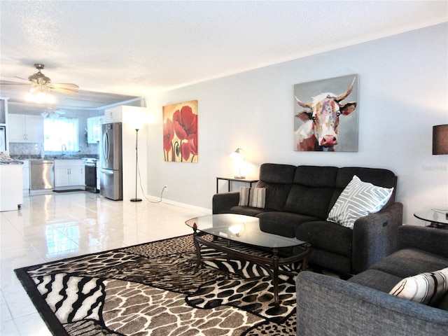 living area featuring a ceiling fan, a textured ceiling, and baseboards