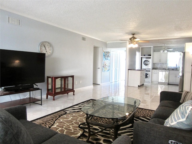 living room featuring visible vents, crown molding, a textured ceiling, and stacked washing maching and dryer