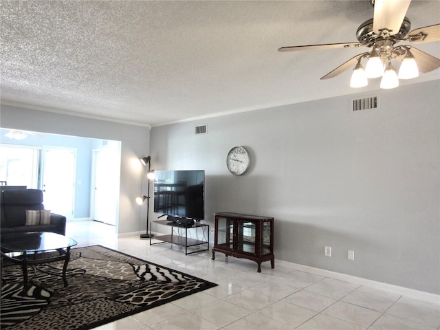 living area with a textured ceiling, baseboards, visible vents, and crown molding