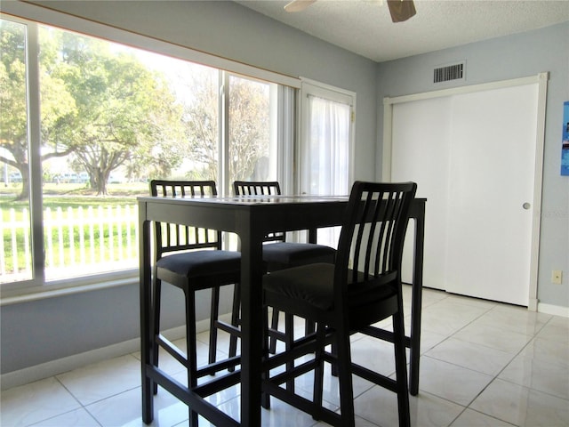 dining space featuring visible vents, a textured ceiling, baseboards, and light tile patterned floors