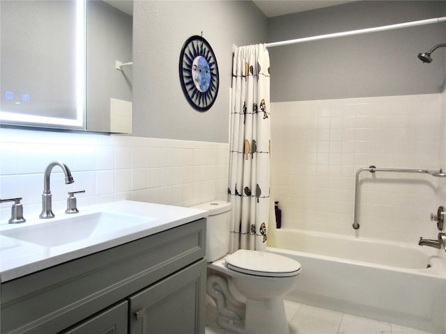 full bathroom with toilet, tile patterned flooring, shower / bath combo with shower curtain, vanity, and tile walls