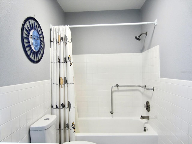 bathroom with a wainscoted wall, shower / tub combo with curtain, tile walls, and toilet